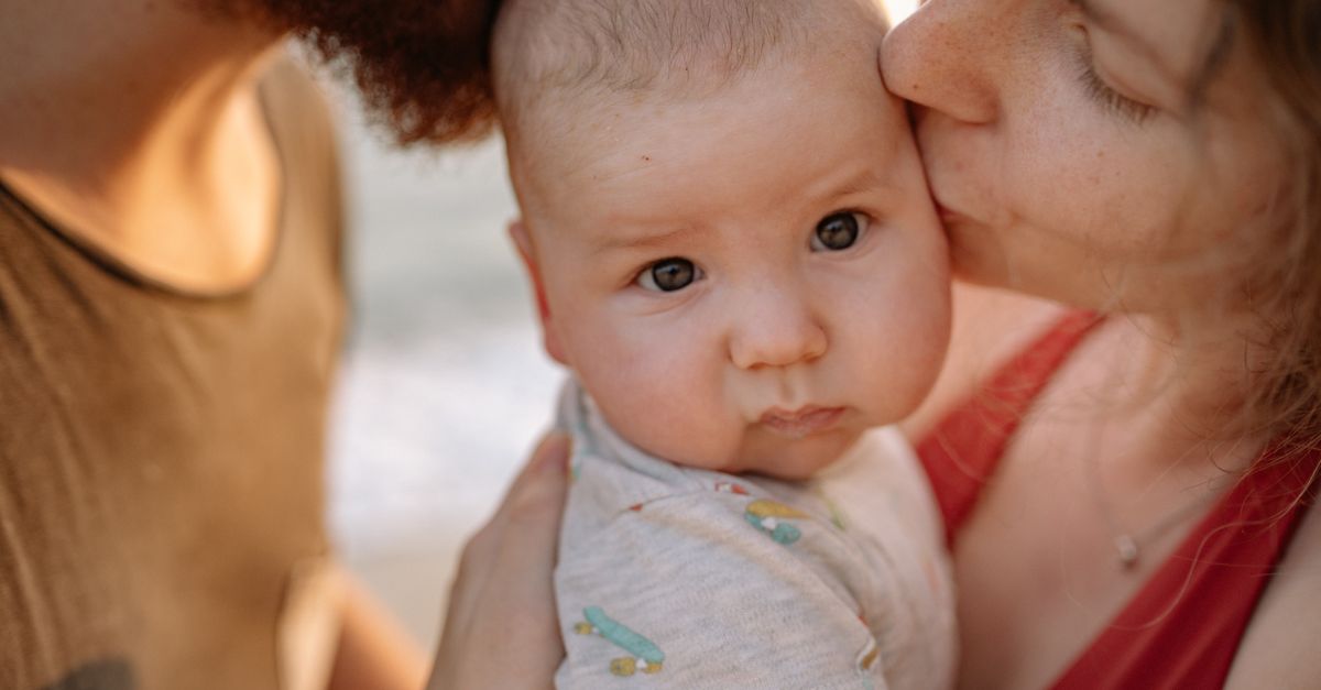 A tender moment of parents kissing their baby, highlighting love and family bonds.